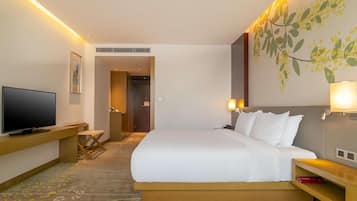 A hotel room with a bed, a TV, a desk, and a lamp.