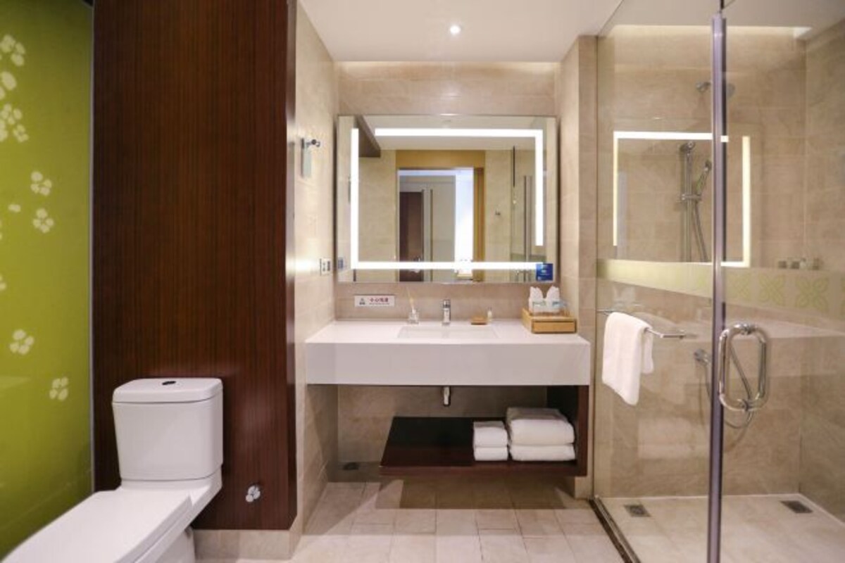 A modern bathroom with a toilet, a sink with a mirror, and a glass-enclosed shower.