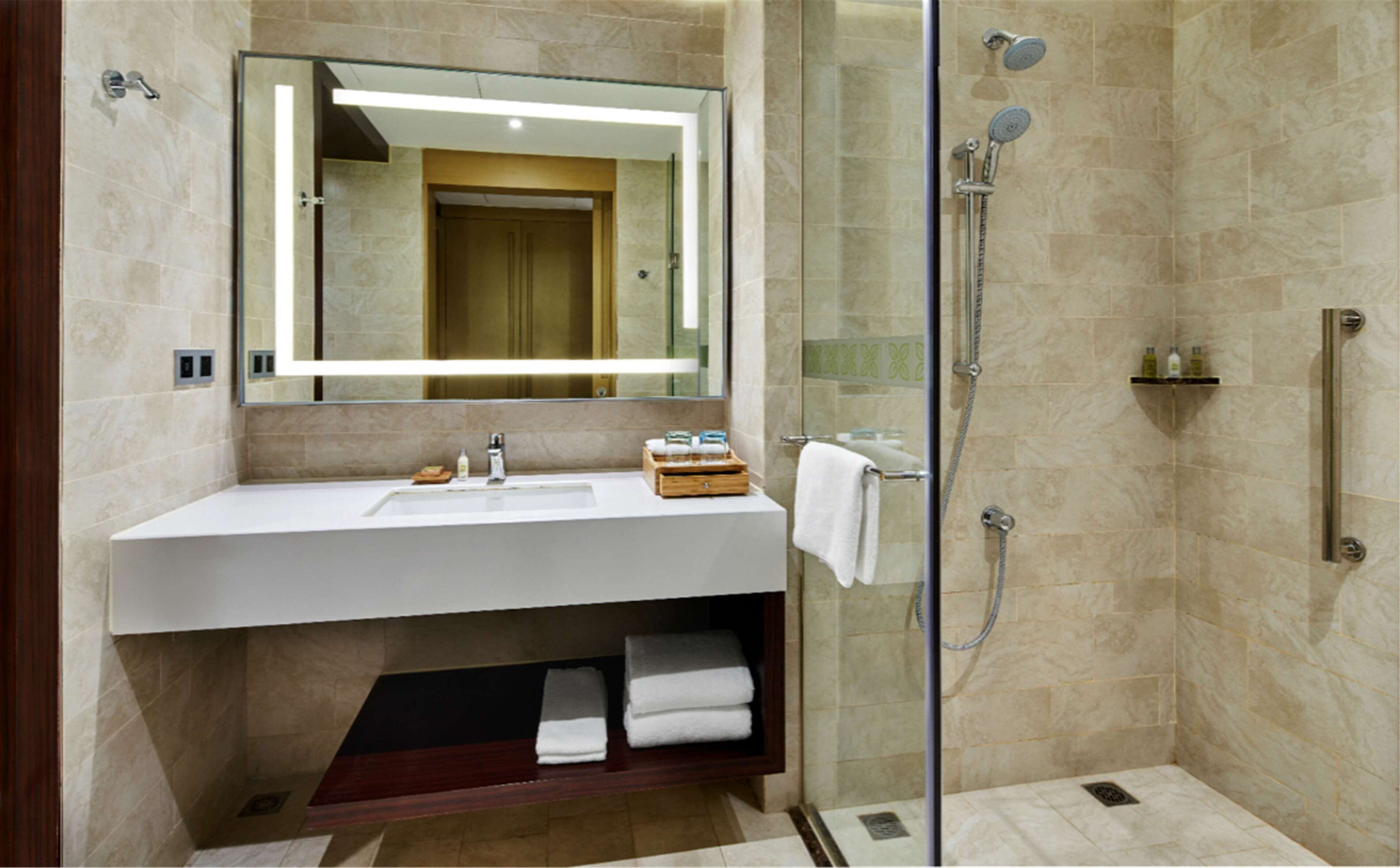 A modern bathroom with a glass-enclosed shower, a white sink, and a mirror above it.