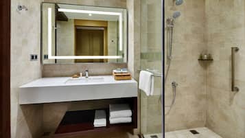 Un baño moderno con ducha envuelta en cristal, un lavabo blanco y un espejo encima.