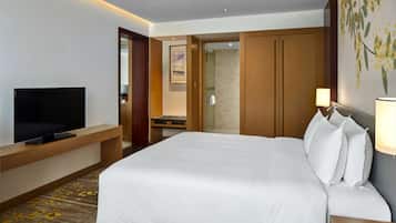 A hotel room with a large bed, a flat-screen TV, a desk, and a wardrobe.