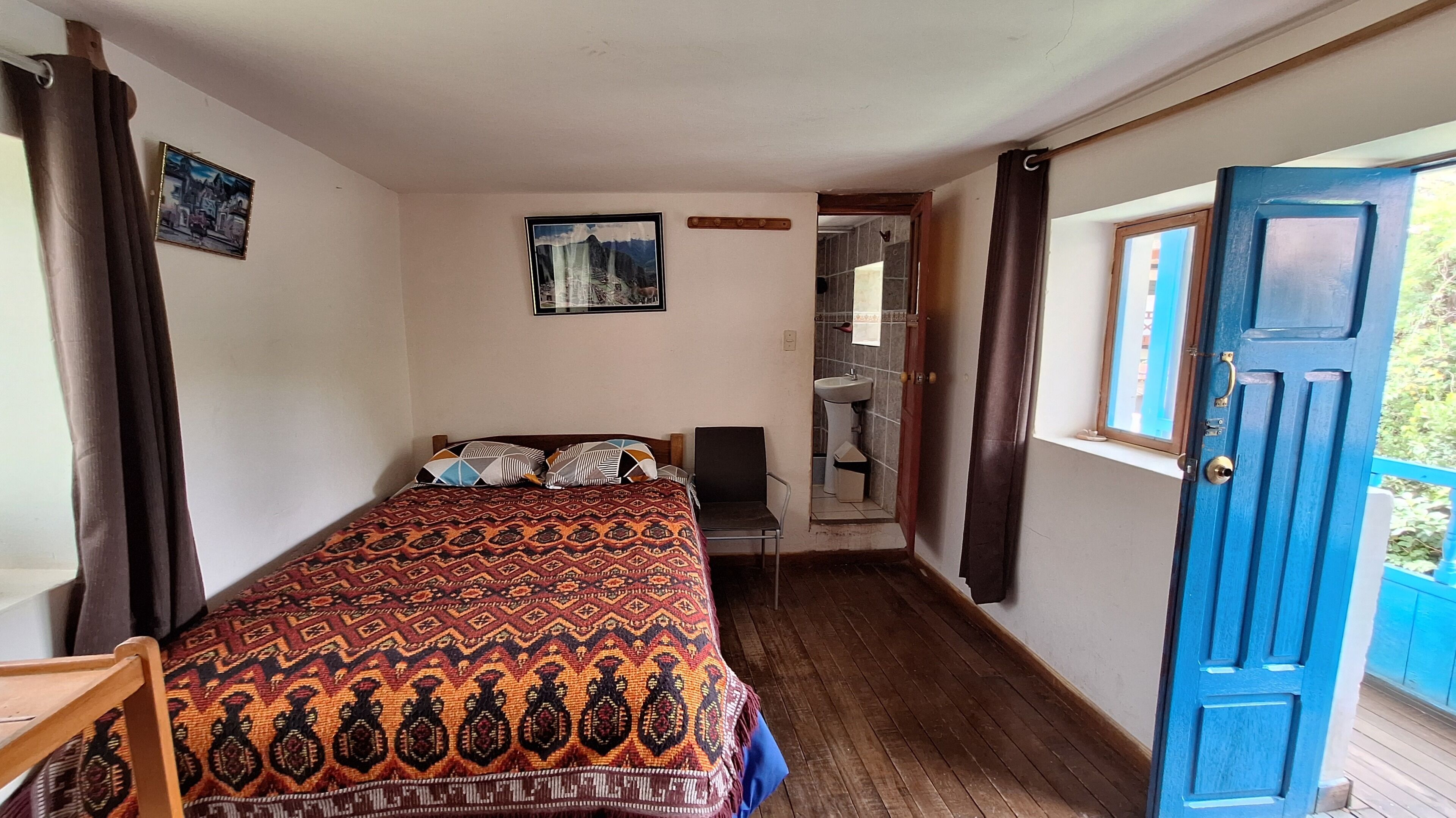 Un dormitorio con cama, una silla, una ventana y una puerta.