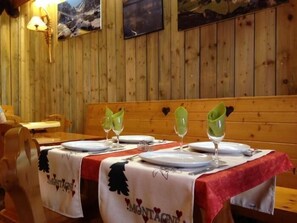 A restaurant with wooden walls and a bench. Tables are set with plates, glasses, and cutlery. - Le Pas de L'Ours (Cauterets)