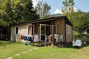 A small, single-story cabin with a porch, a table, chairs, and a dog. - Le Pas de L'Ours (Cauterets)