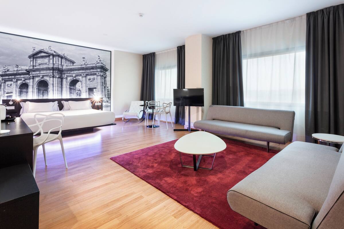 Ein modernes Wohnzimmer mit einem großen Bett, einem Sofa, einem Couchtisch und einem Fernseher.