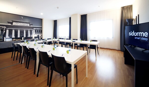 Una sala conferenze con un grande tavolo, sedie e uno schermo televisivo che mostra 'sidorme smart sleep'.