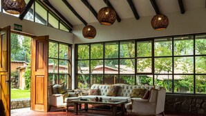 A spacious room with a large window, a sofa, a coffee table, and hanging wicker lamps. - Andean Wings Valley (Urubamba)