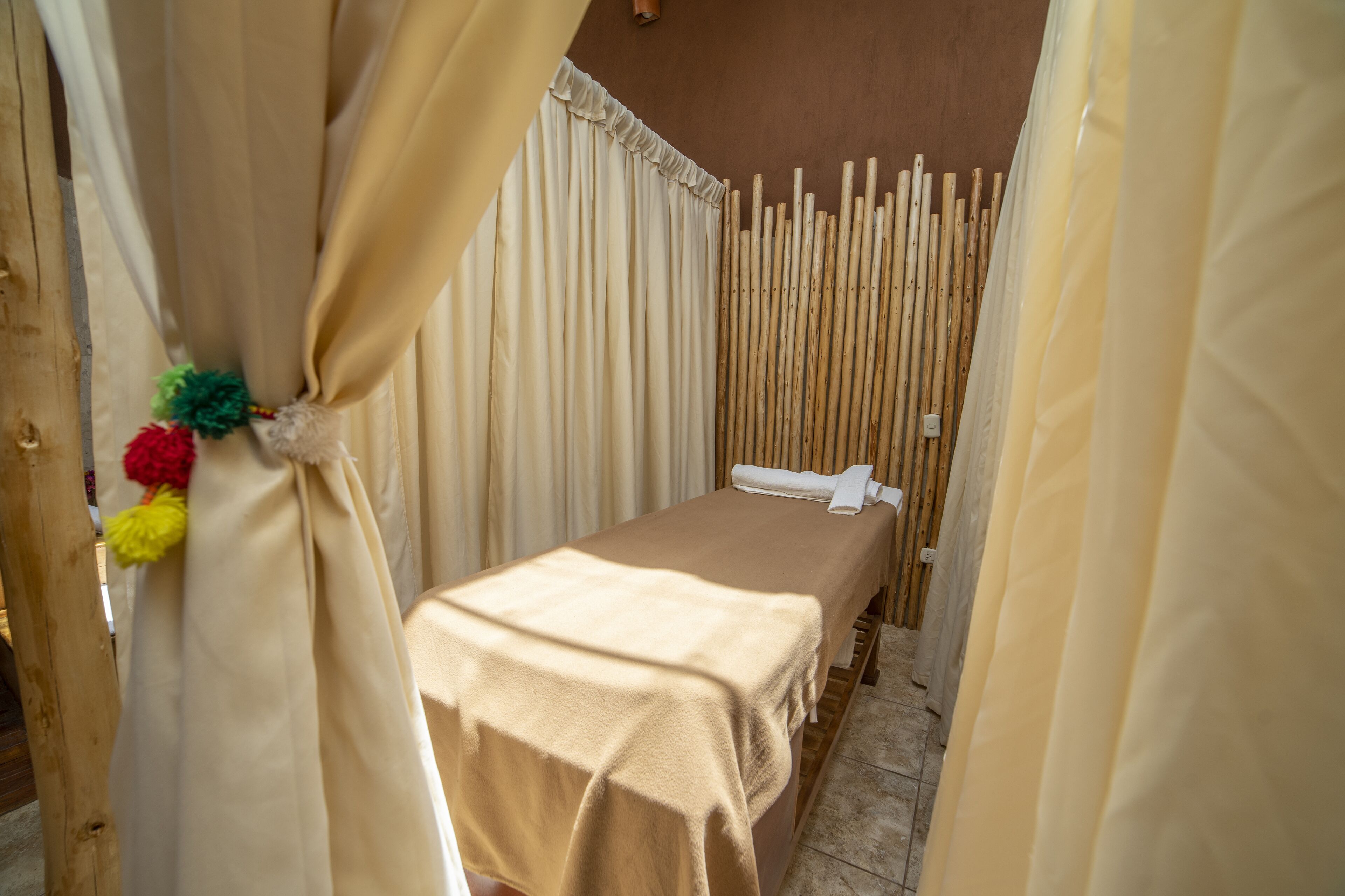 Une petite chambre privée, avec un lit simple, des rideaux de couleur beige et une cloison en bois.