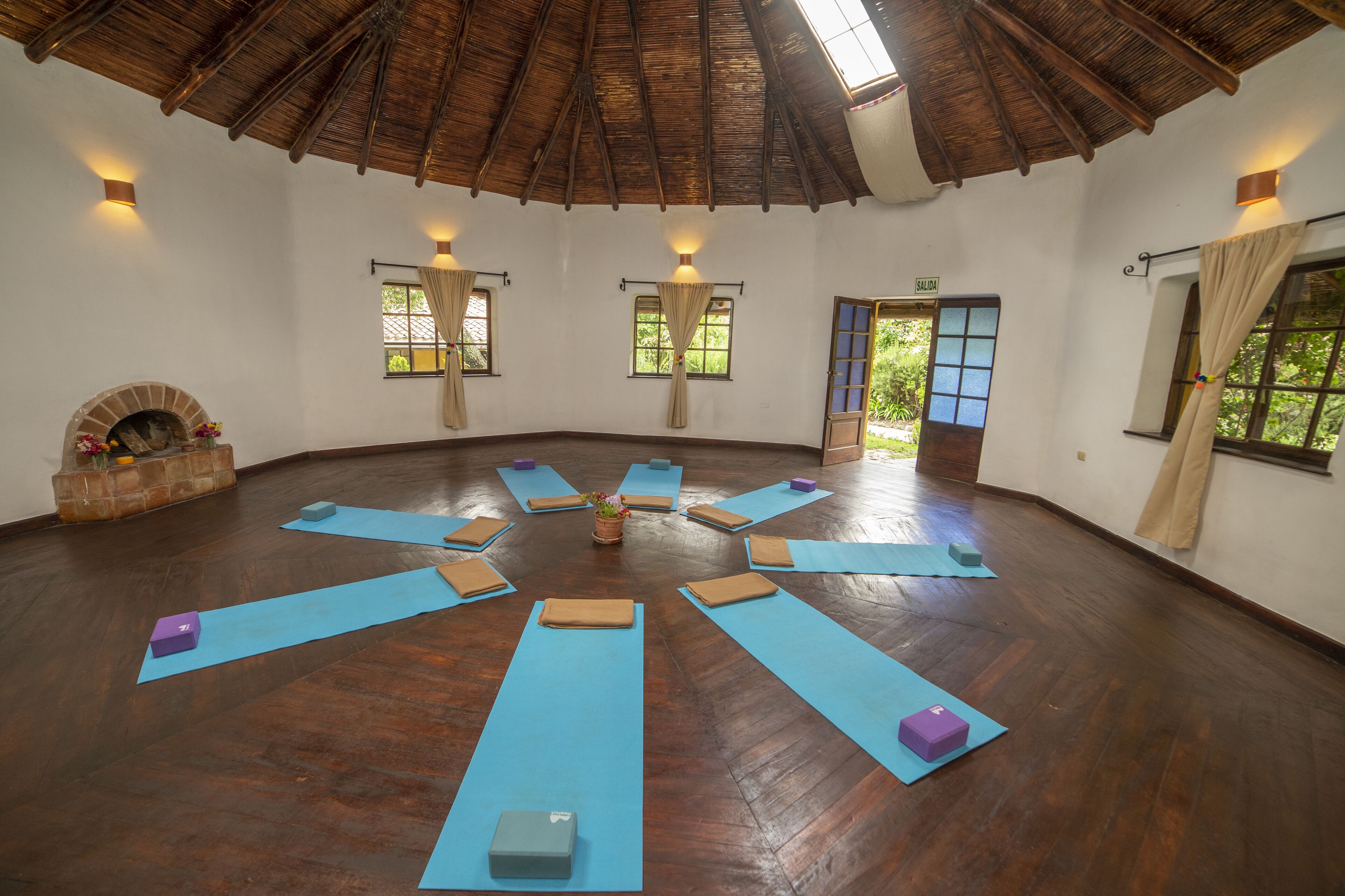 Une pièce spacieuse dotée d’un plancher en bois, aménagée avec des tapis bleus et de petits blocs pour les exercices.