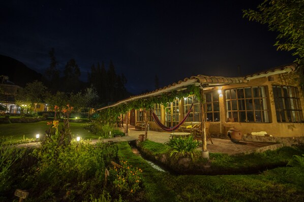 A well-lit outdoor area with a patio, seating, and a hammock. - Andean Wings Valley (Urubamba)