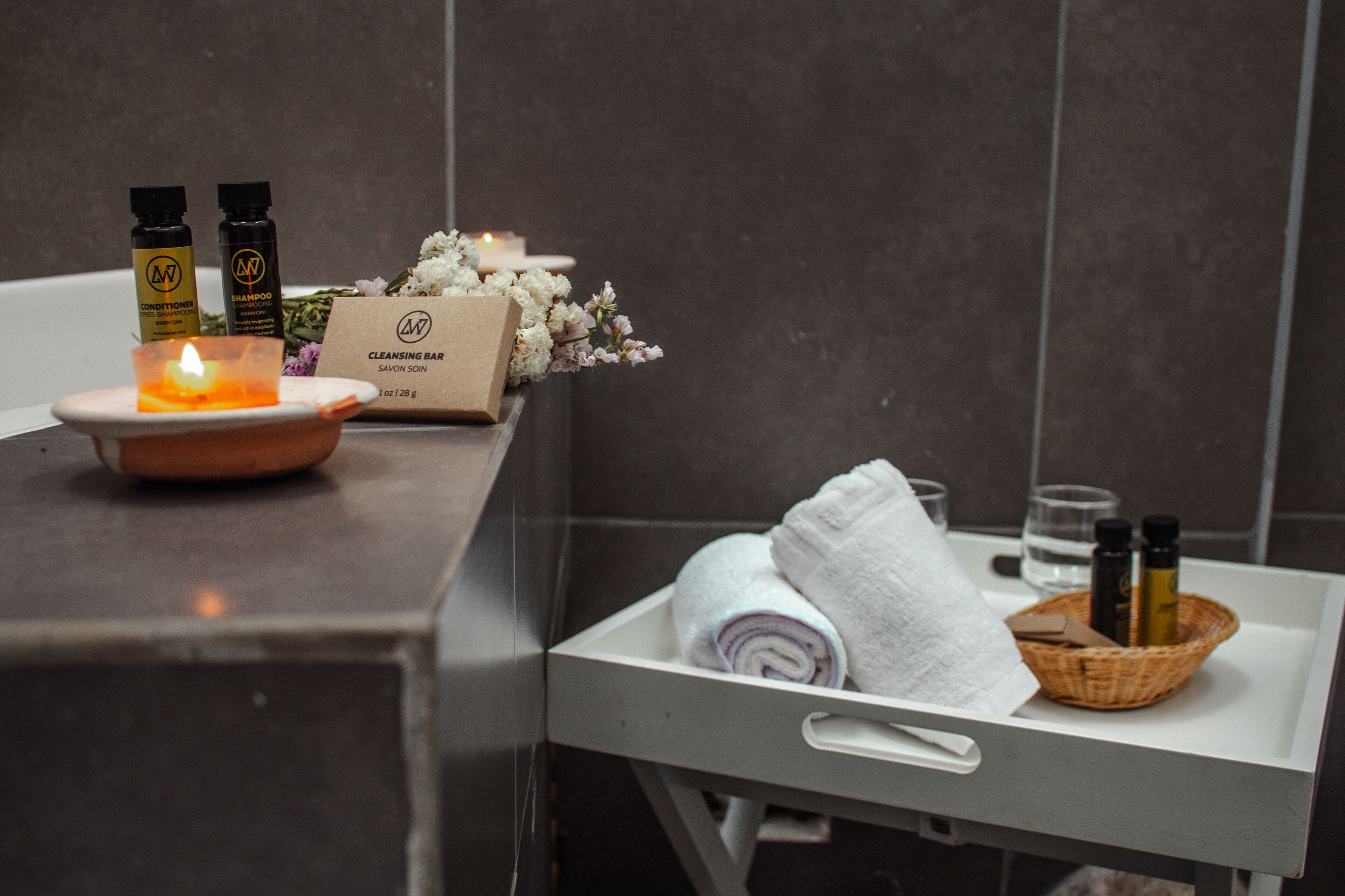 Un meuble-lavabo dans une salle de bain avec une bougie, des articles de toilette et des serviettes.