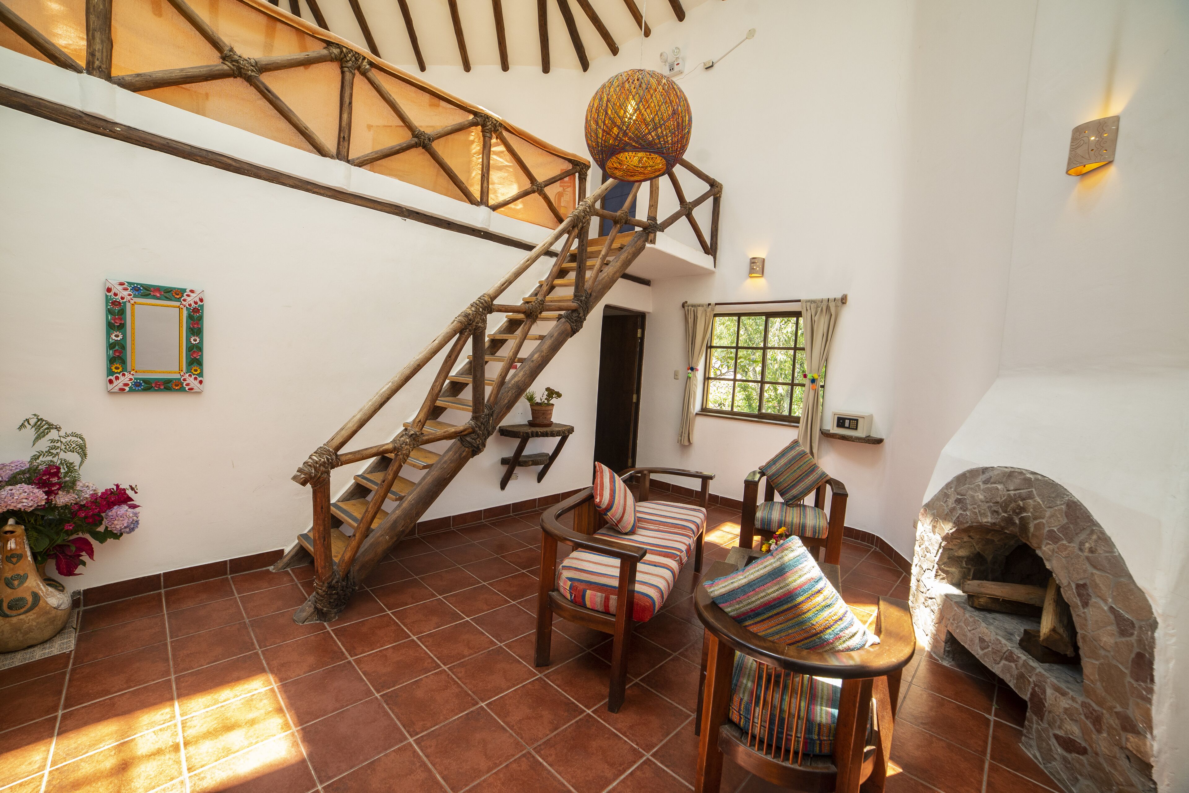 Un vaste espace de vie agrémenté d’un escalier en bois, d’une cheminée en pierre et d’une grande fenêtre laissant entrer la lumière naturelle.