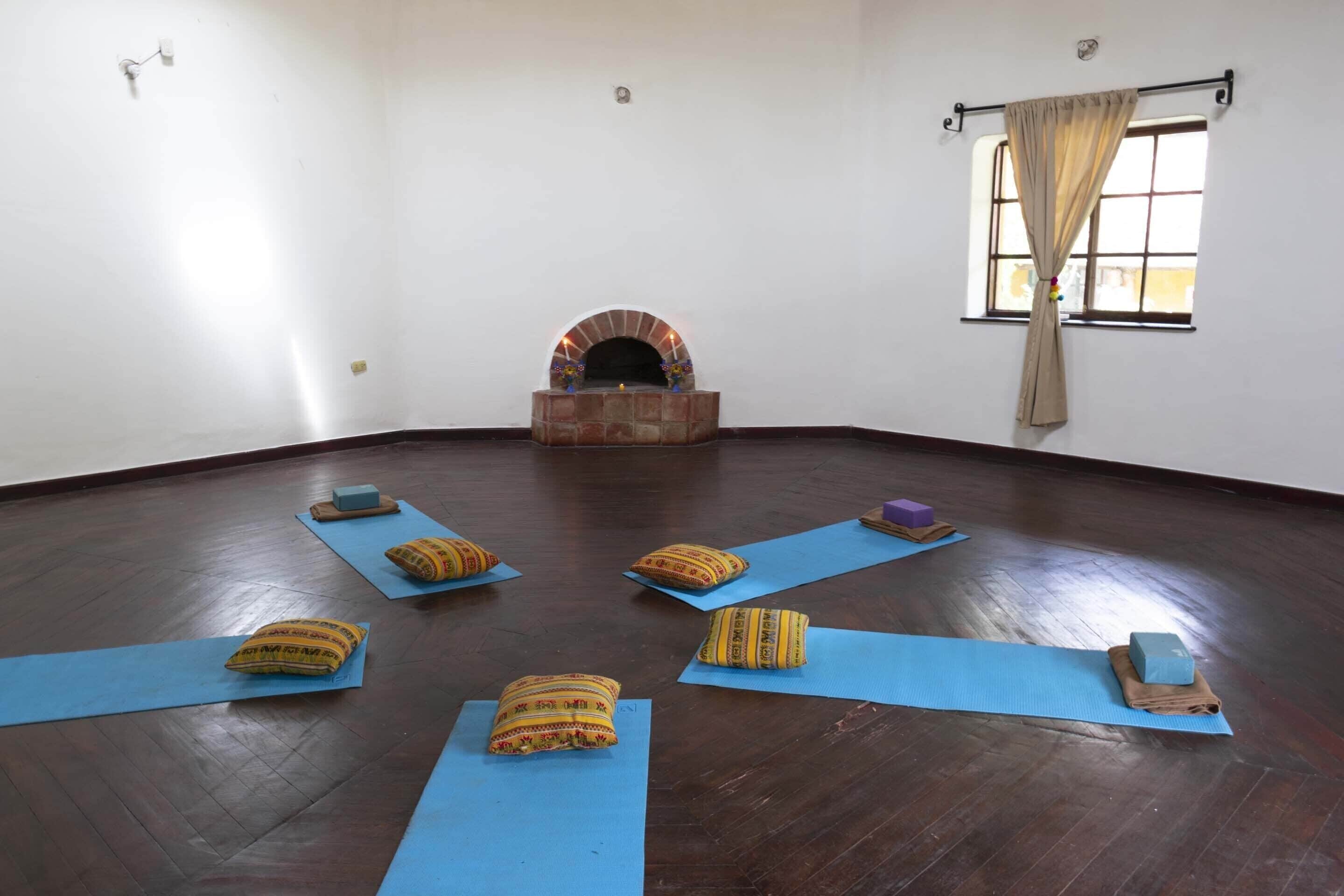 A room with a brick fireplace, yoga mats, and pillows arranged for a yoga session.