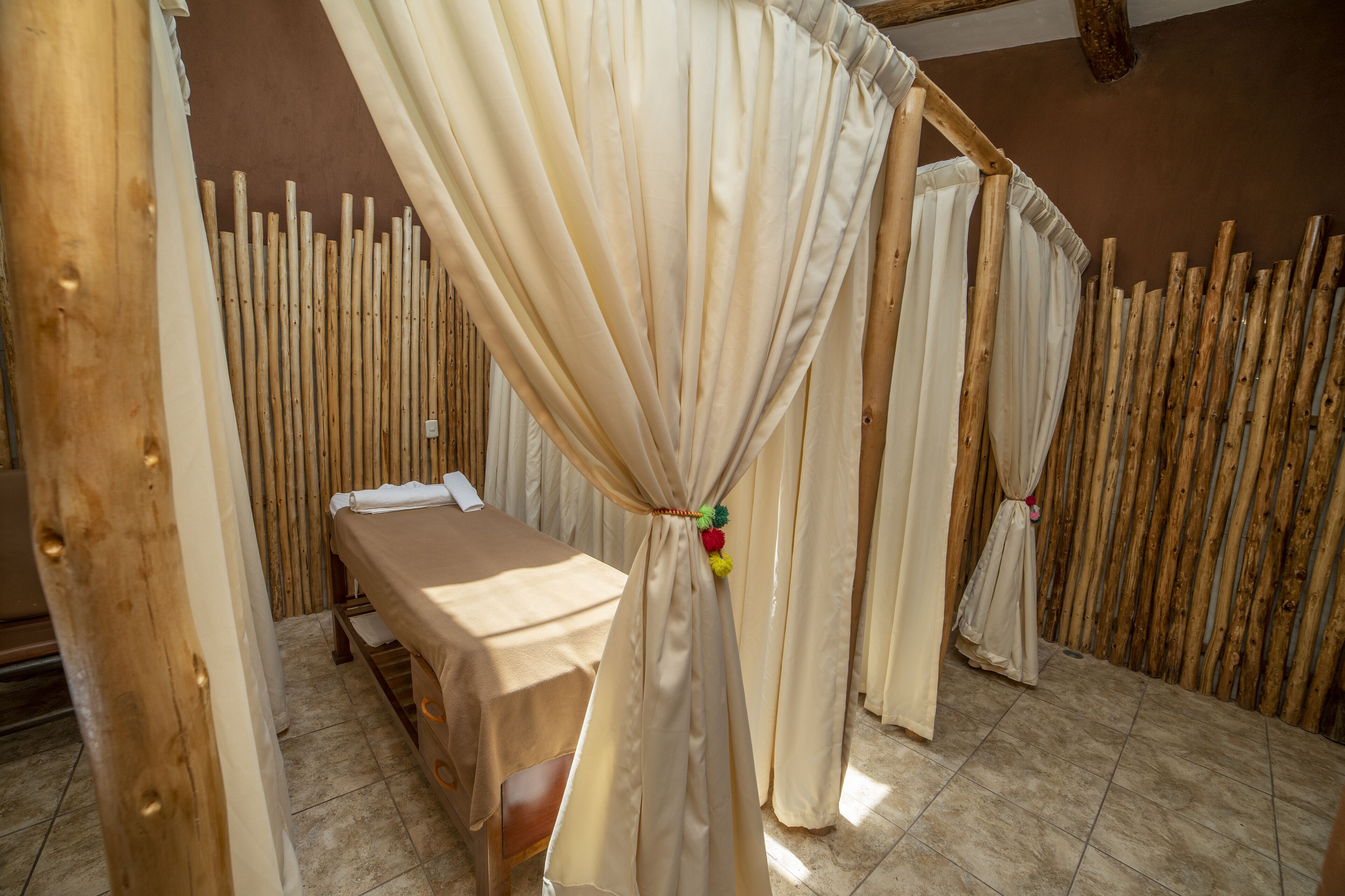 A room with a bed, a wooden headboard, and a curtain with a colorful tassel.