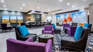 A lobby with purple and gray sofas, a reception desk, and a mural of a desert landscape.
