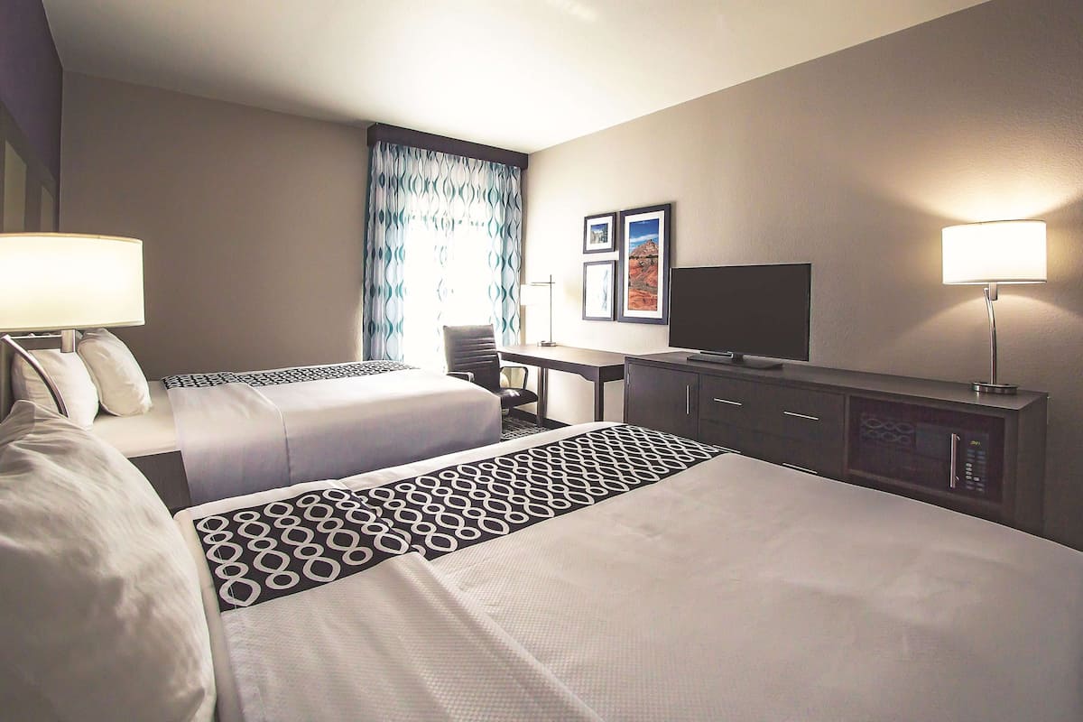 Ett hotellrum med två sängar, ett skrivbord, en tv och en mikrovågsugn.