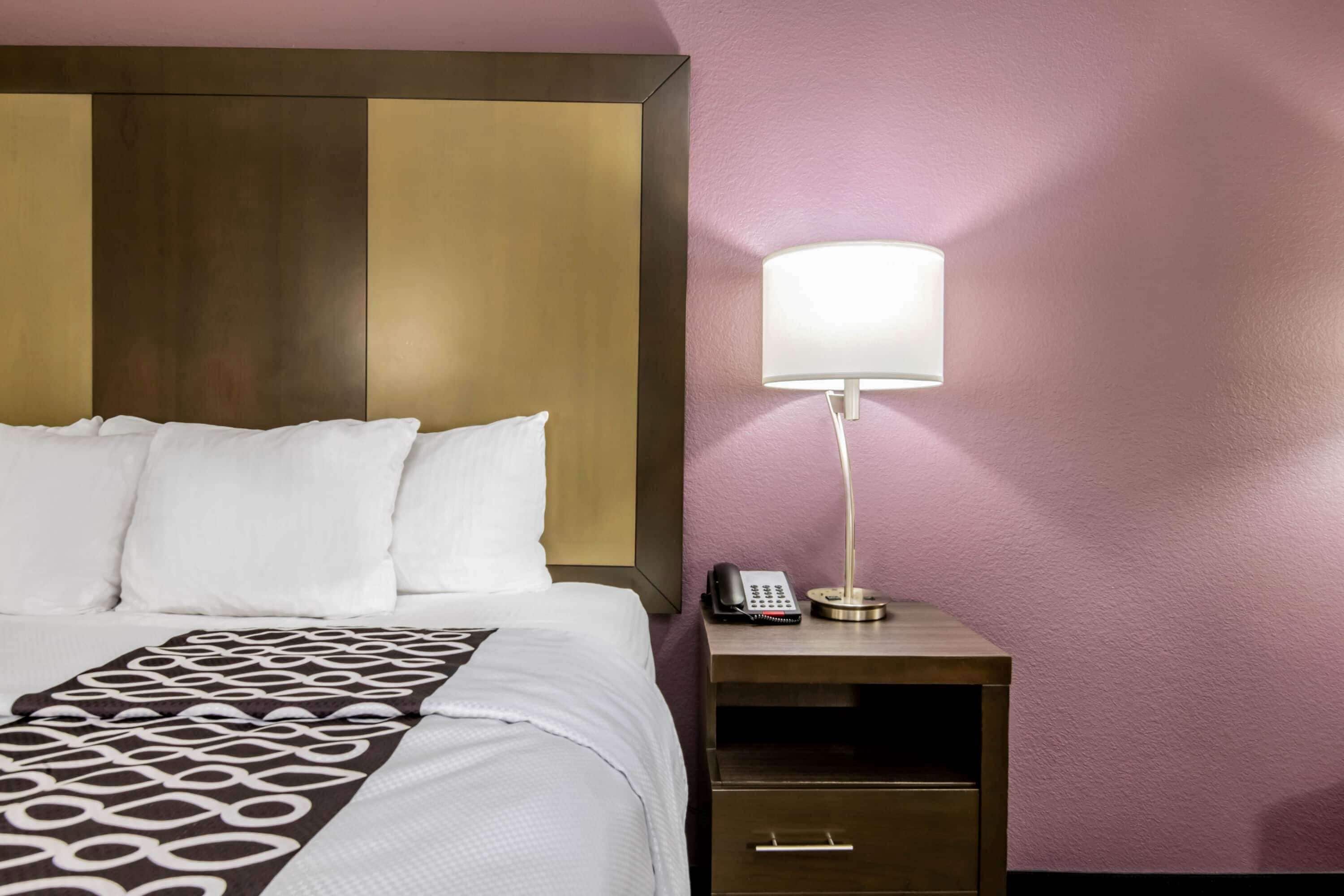 A hotel room with a bed, a bedside lamp, a phone, and a nightstand.