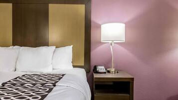 A hotel room with a bed, a bedside lamp, a phone, and a nightstand.