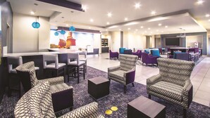 A modern lounge area with seating, a bar, and a flat-screen TV.