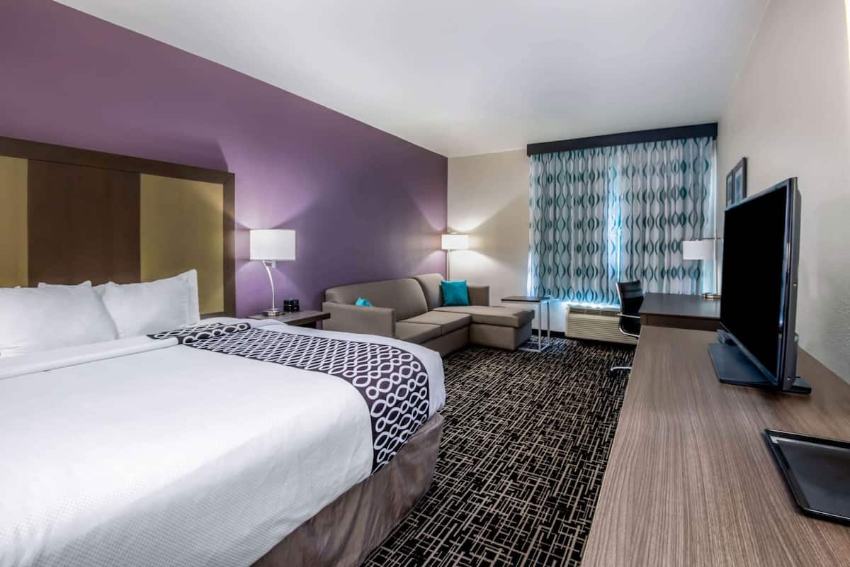 Ett hotellrum med en stor säng, en soffa, en tv och ett skrivbord.