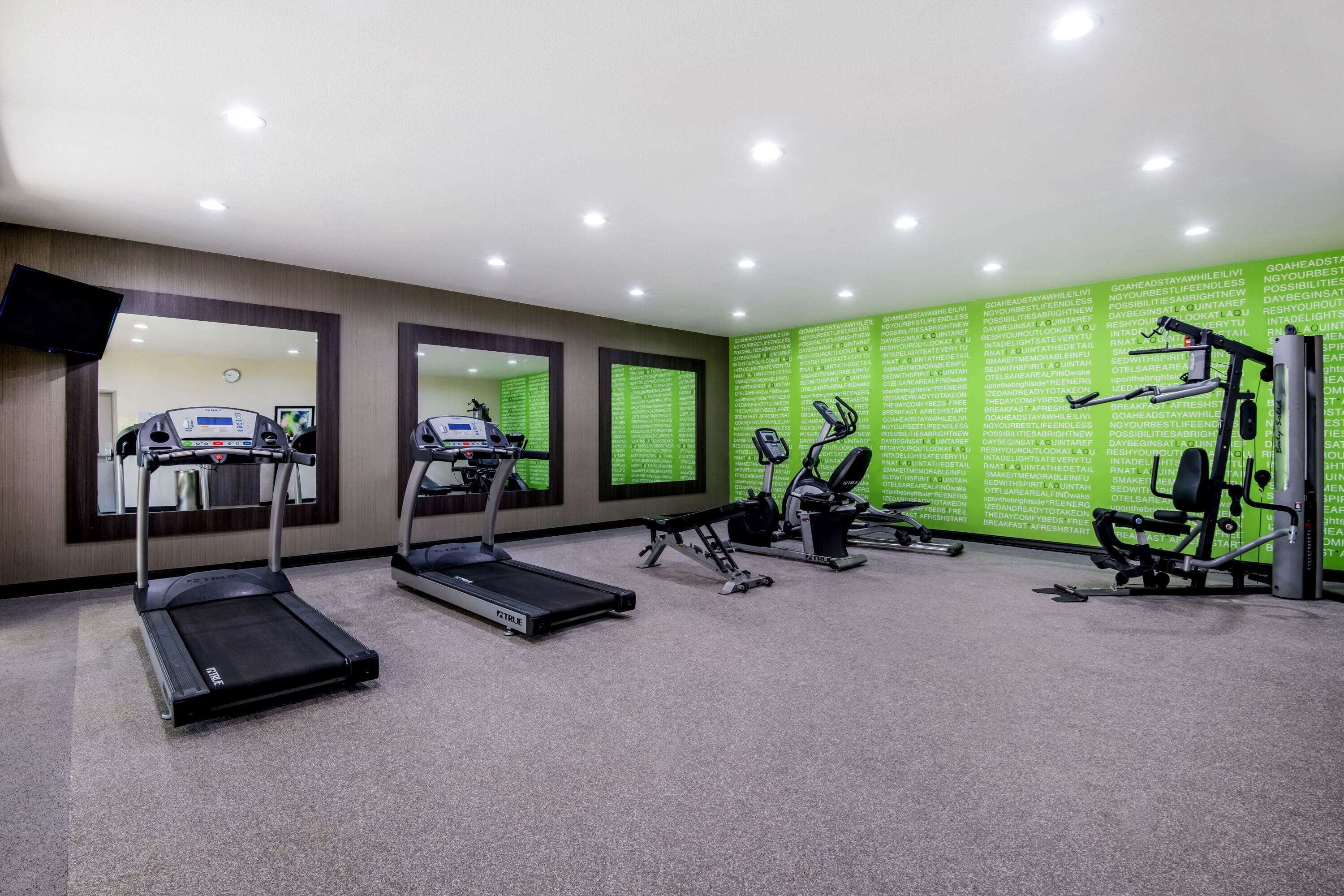 A gym with treadmills, elliptical machines, and weight equipment.