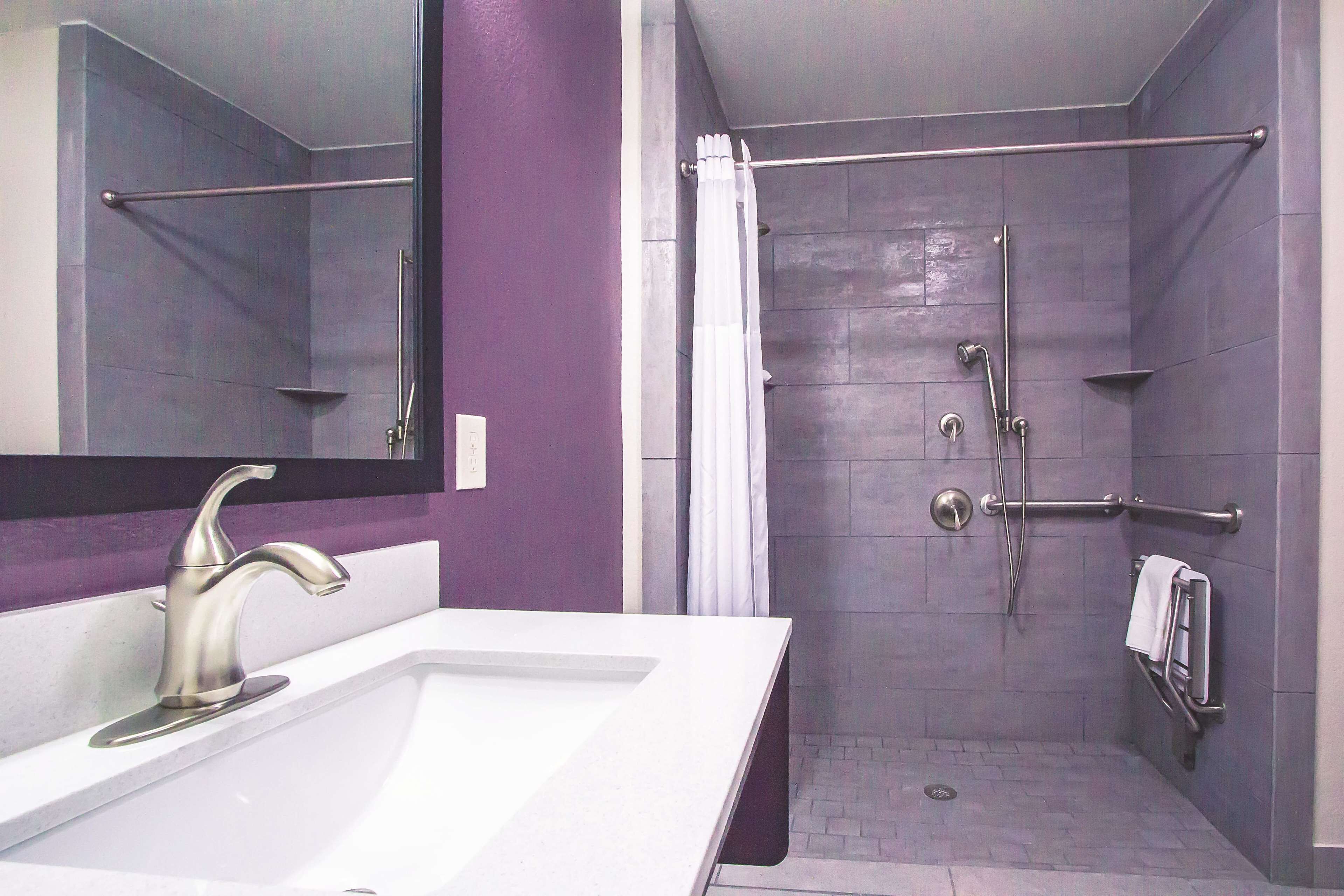 Uma casa de banho moderna com lavatório branco, um espelho grande e um chuveiro duplo com porta de vidro.