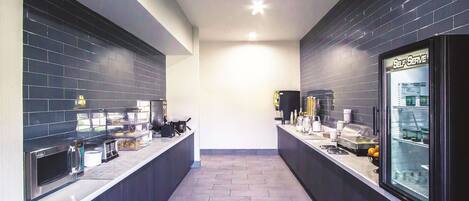 Uma cozinha moderna com paredes revestidas de azulejos escuros, eletrodomésticos de aço inoxidável e um espaço para autoatendimento.