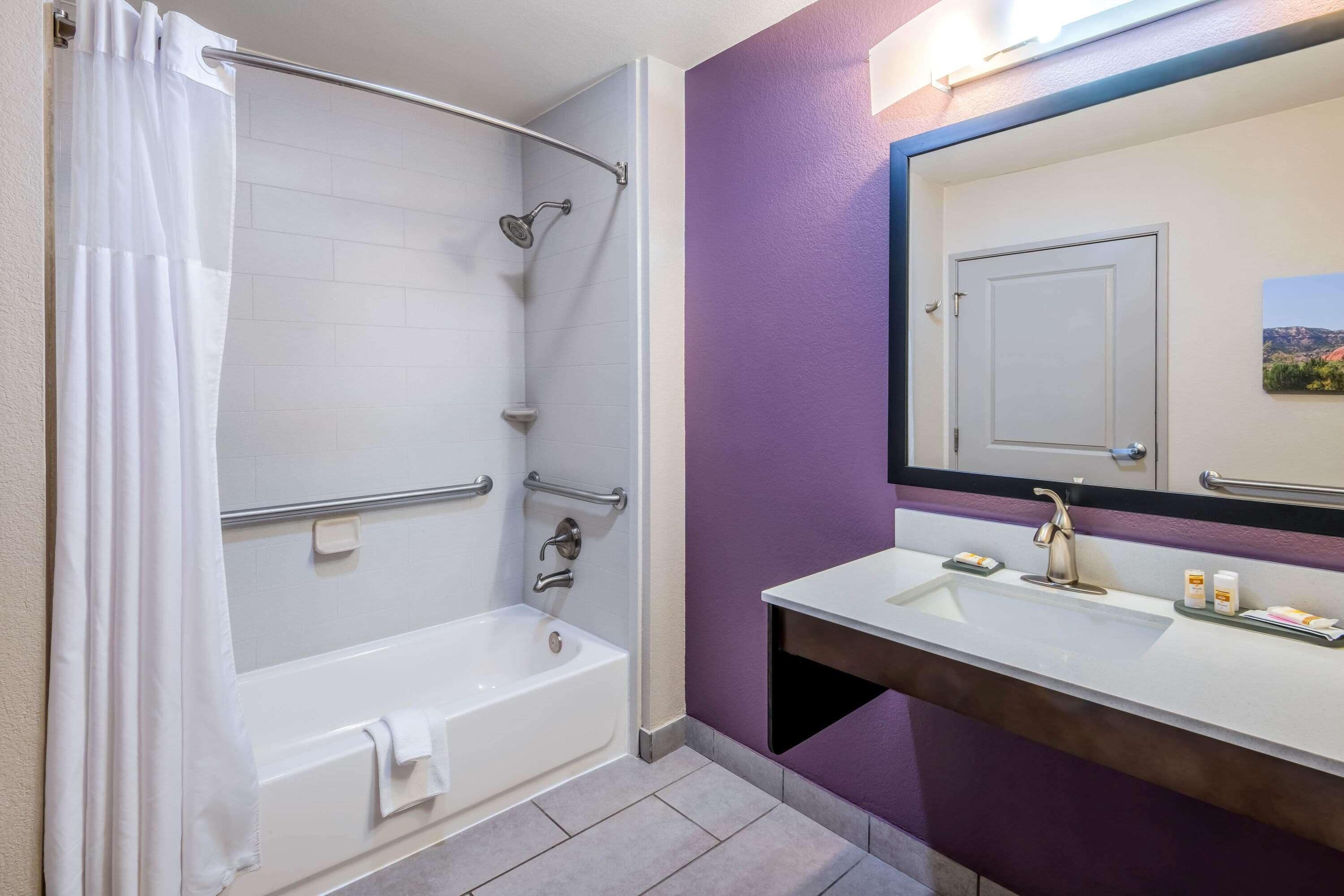 A bathroom with a bathtub, shower, and sink with a mirror.