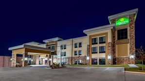 A hotel with a modern design, featuring a prominent 'La Quinta' sign, multiple entry points, and a well-lit exterior.