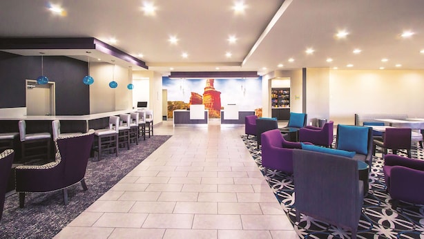 A hotel lobby with a reception desk, seating area, and a patterned carpet.