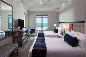A hotel room with two beds, a desk, a chair, a large mirror, and a view of the sea. - Treasure Island Beach Resort (Treasure Island)
