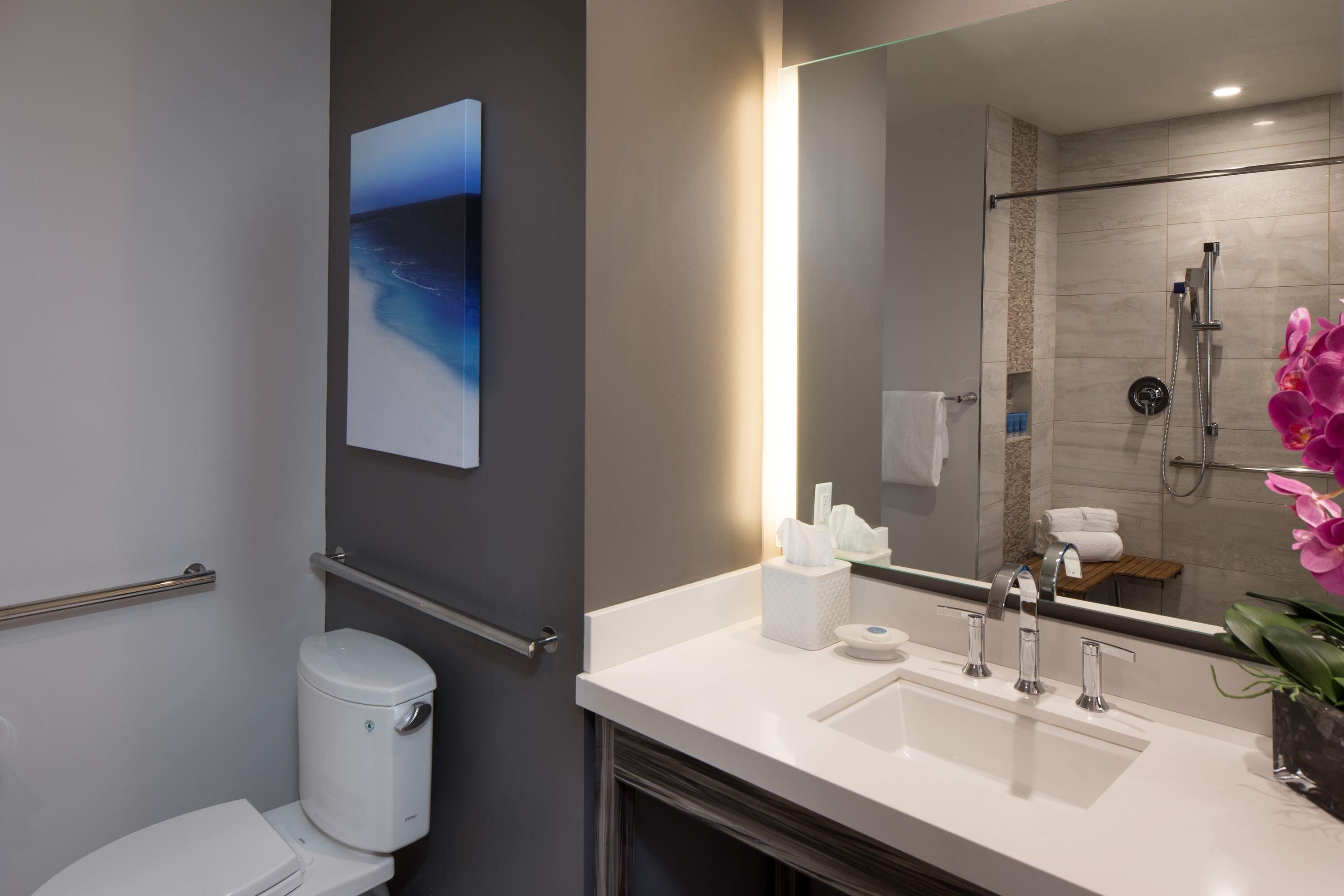 Ein modernes Badezimmer mit Toilette, Waschbecken, Dusche und einem großen Spiegel.