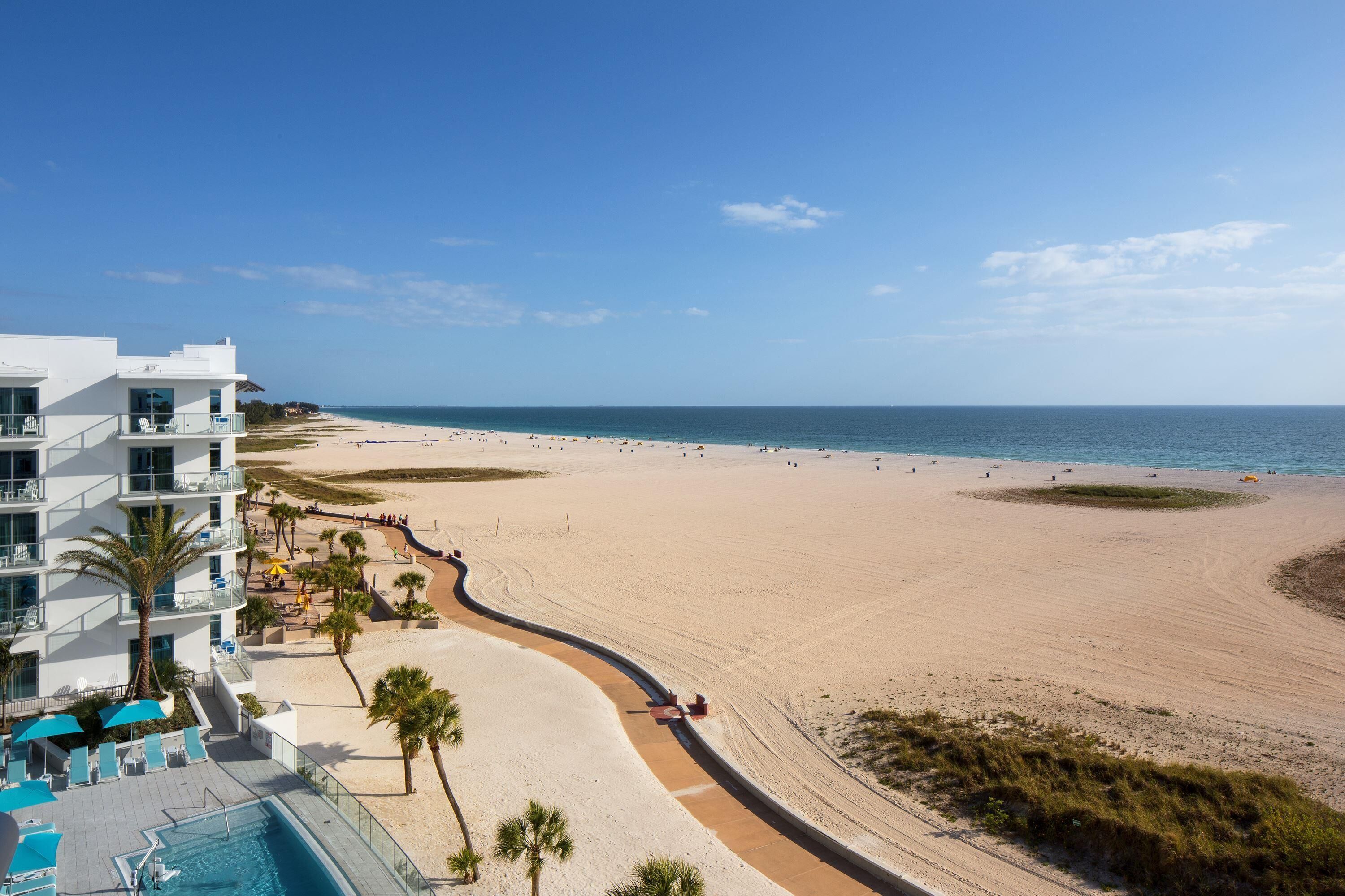 A beachfront hotel with a swimming pool, beach access, and a clear view of the ocean.