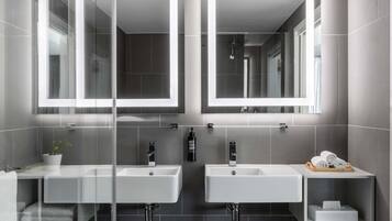 Un baño moderno con dos lavamanos, un espejo y un perchero para toallas.