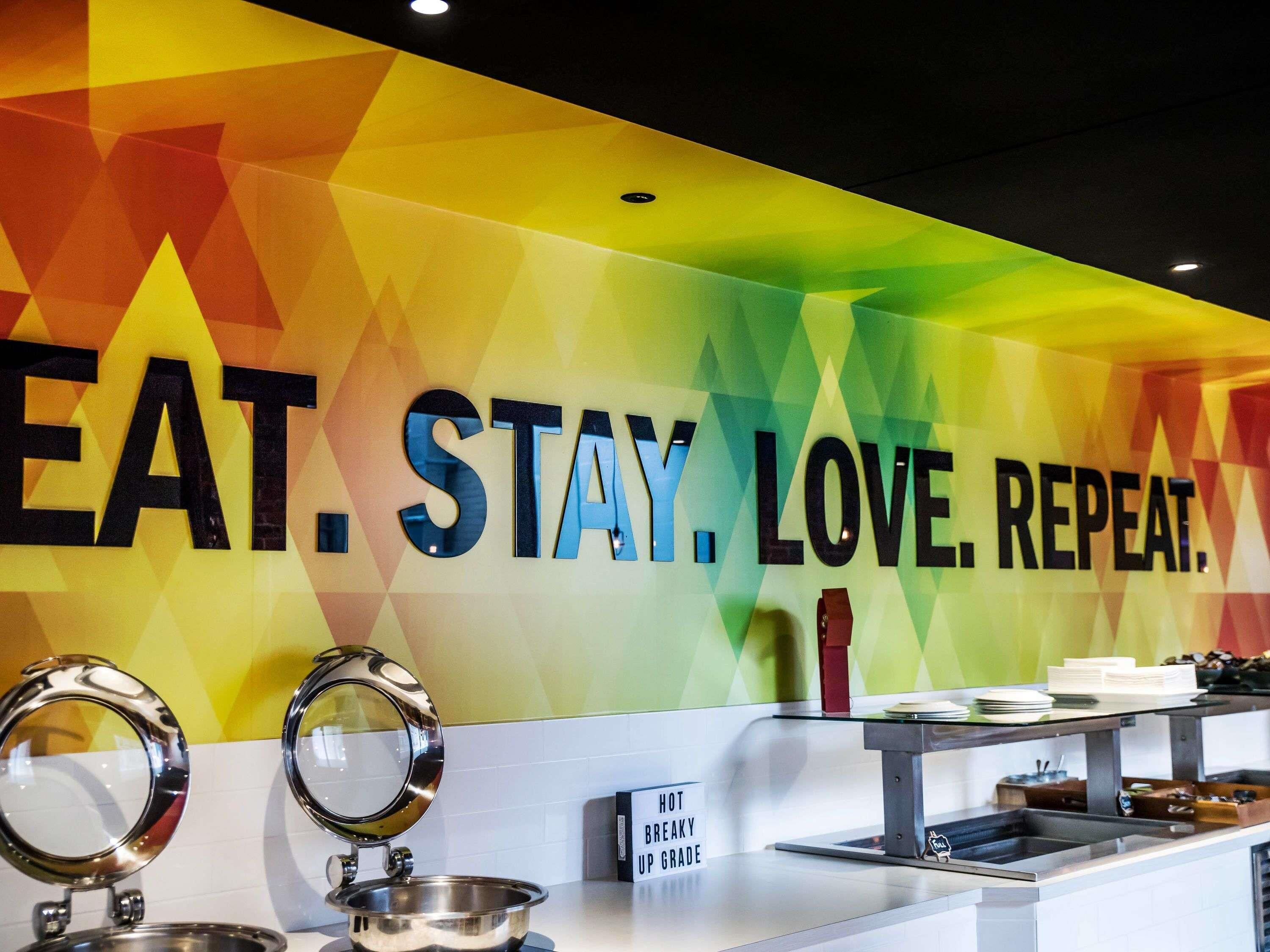A wall with the phrase "EAT. STAY. LOVE. REPEAT." and a sign indicating "HOT BREAKY UP GRADE".