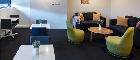 Ein stilvoller Lounge-Bereich mit einer Couch, Sesseln, einem Couchtisch und einem kleinen Tisch mit einer Pflanze.