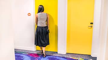 A person standing in front of a yellow door in a hallway with a colorful carpet.