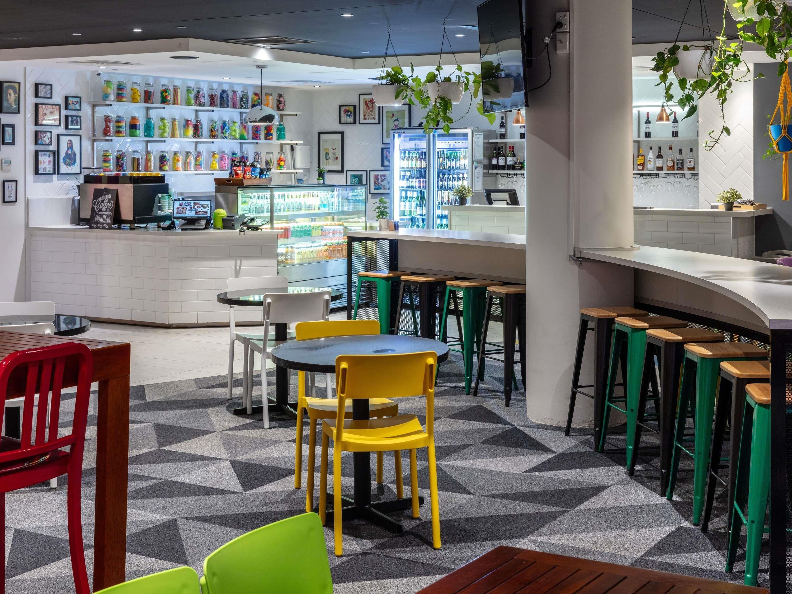 A café with a bar area, seating, and a display of colorful drinks.