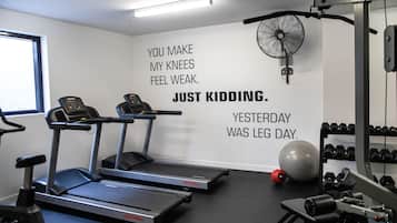 A gym with treadmills, a fan, and a wall with motivational text.