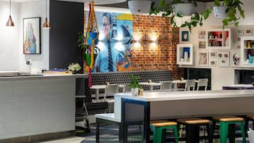 Un interior de restaurante moderno con un mural de ladrillo, plantas colgantes y una zona de bar.