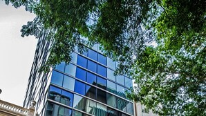 Un hotel con fachada clásica, un edificio moderno de cristal en la parte superior y un letrero verde que indica que es un hotel.