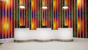 Un mostrador de recepción con un diseño de pared geométrico y colorido y dos lámparas colgantes.