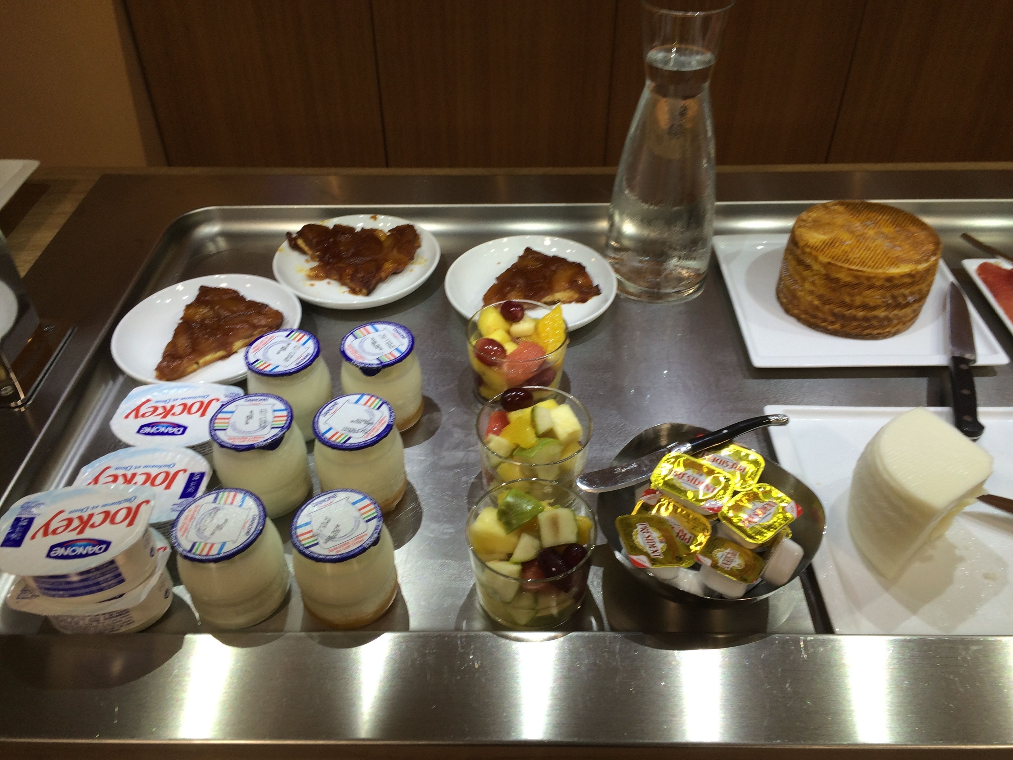 Un plateau contenant divers aliments, notamment du yaourt, une salade de fruits et un gâteau.