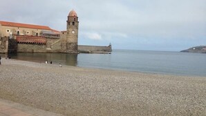 A coastal fort with a tower, a pebbled beach, and a calm sea. - ibis Styles Collioure Port Vendres (Port-Vendres)