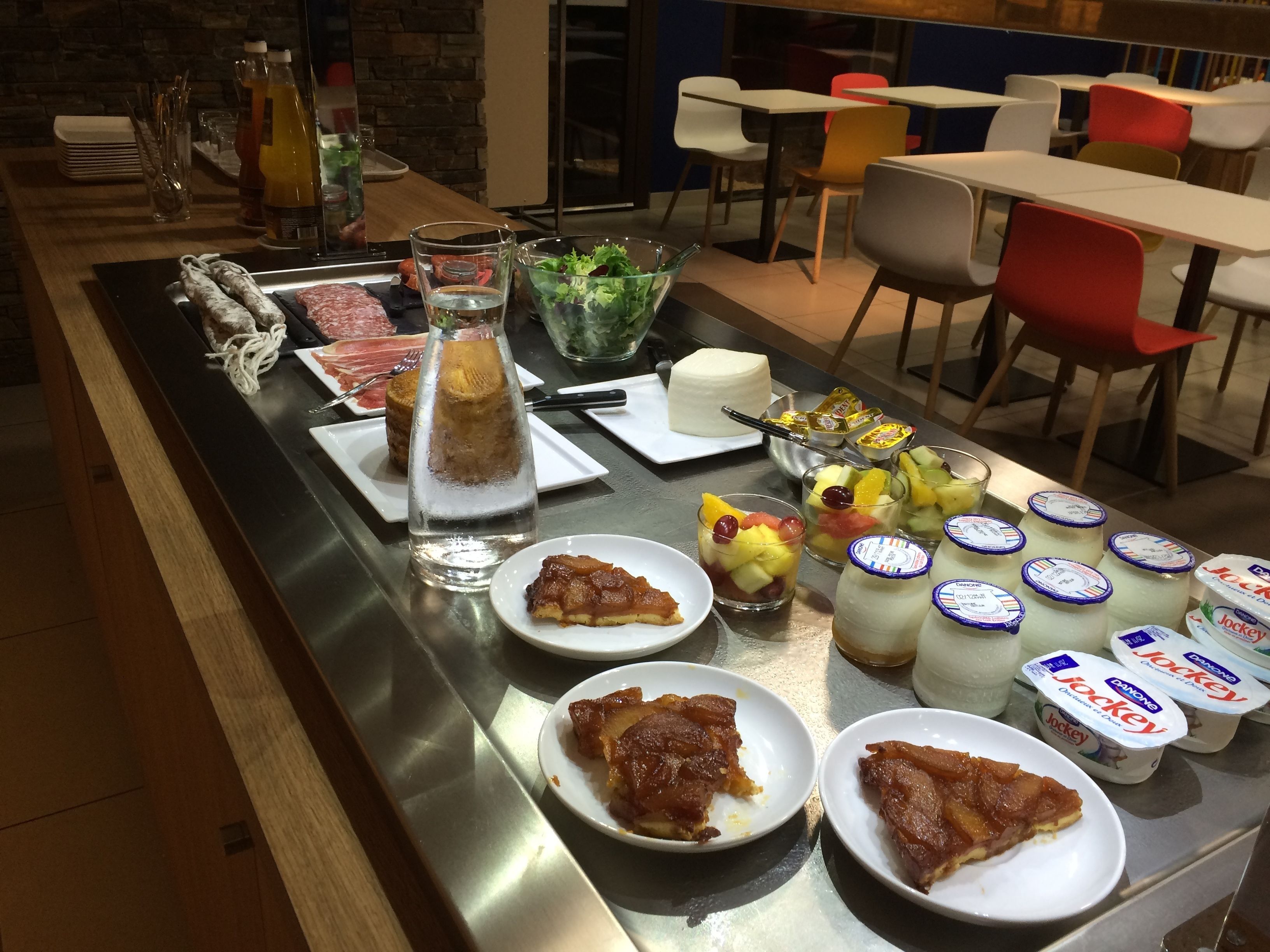 A buffet with various food items, including plates of meat, fruit, and dairy products.