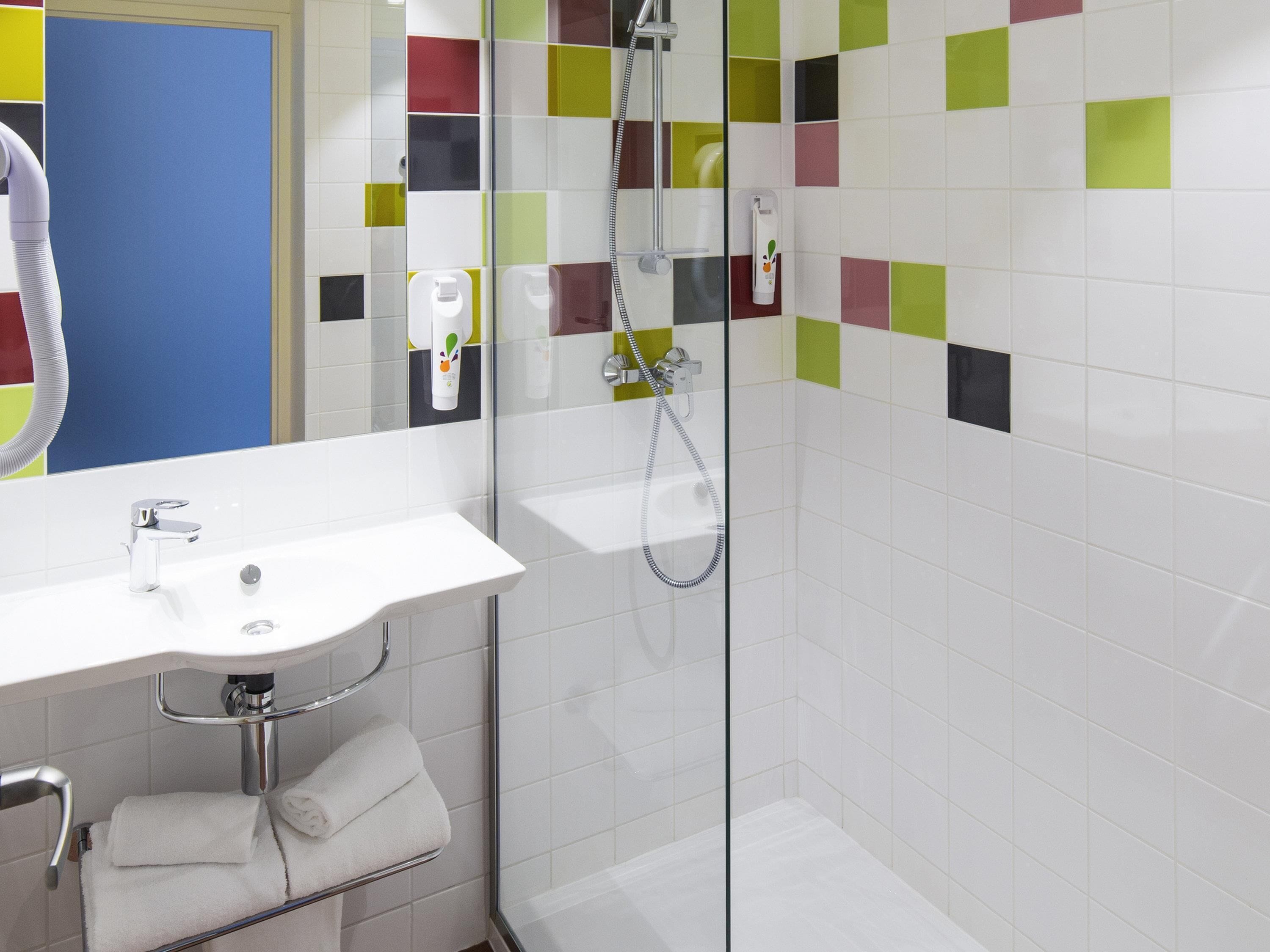 A bathroom with a white sink, a glass shower enclosure, and a mirror.
