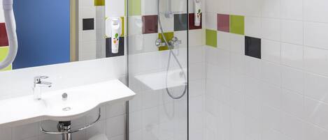 A bathroom with a white sink, a glass shower enclosure, and a mirror.