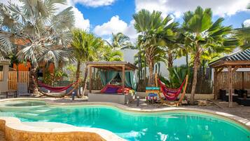 Relax by the serene pool surrounded by lush vegetation and shaded seating areas.