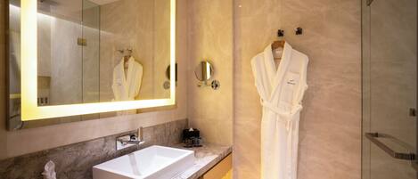 Une salle de bain moderne avec un grand miroir, un lavabo blanc et une douche à parois de verre.