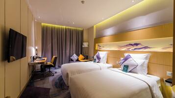 A hotel room with two beds, a desk, a chair, a TV, and a painting on the wall.